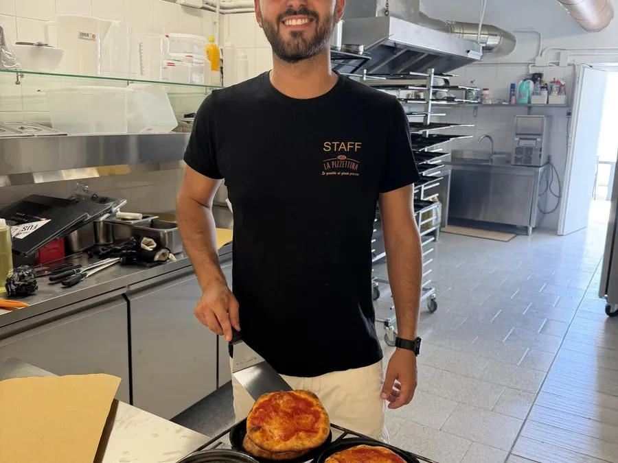 Il nostro pizzaiolo al lavoro in cucina con le teglie